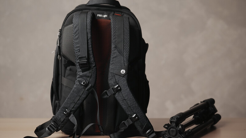 Black camera backpack displayed from rear view showing padded shoulder straps and ventilated mesh backing.