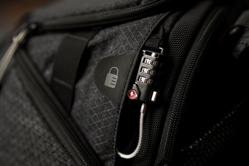 Close-up of a black combination padlock attached to a camera bag zipper.