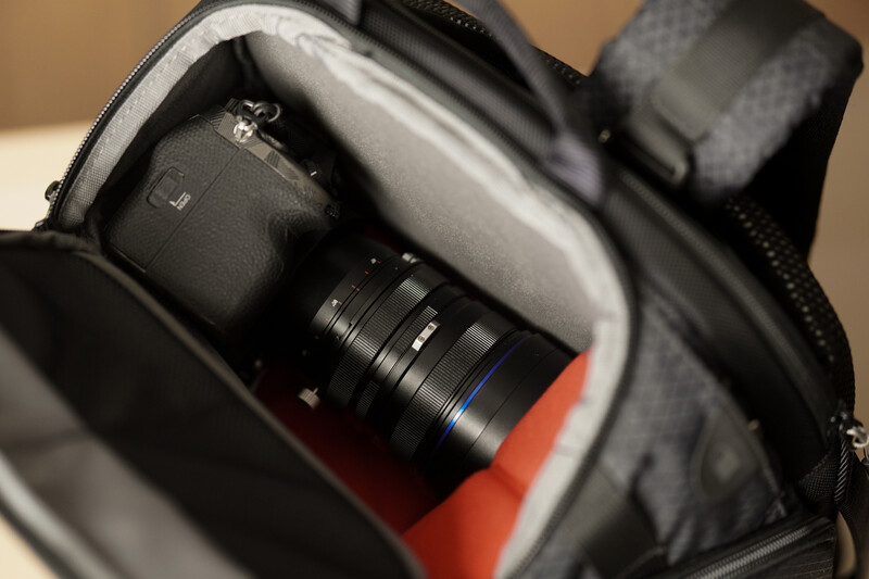 Camera gear packed in a protective case with foam padding and orange accent fabric.