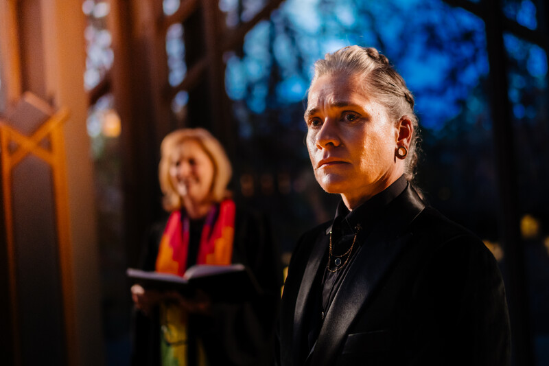 Man in black jacket photographed at dusk with warm and cool lighting creating strong contrast.