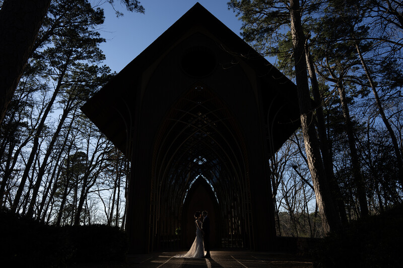 Silhouetted Gothic church interior with pointed arch and figures standing in bright doorway.