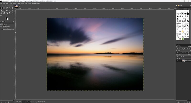 Long exposure landscape photograph of a sunset over calm water with dramatic cloud formations.