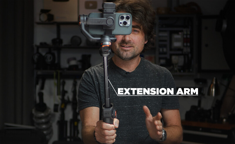 Videographer holding a smartphone mounted on a motorized gimbal stabilizer labeled "Extension Arm."