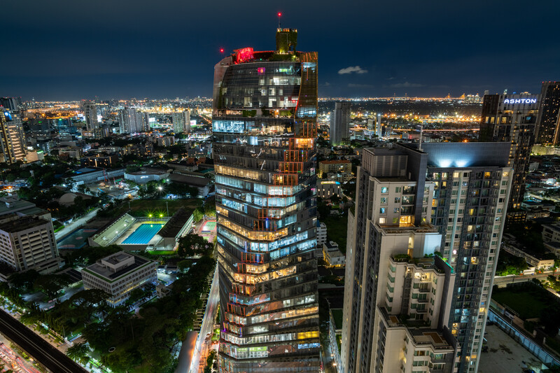 Illuminated high-rise buildings dominating a nighttime cityscape with sprawling urban lights extending to the horizon.