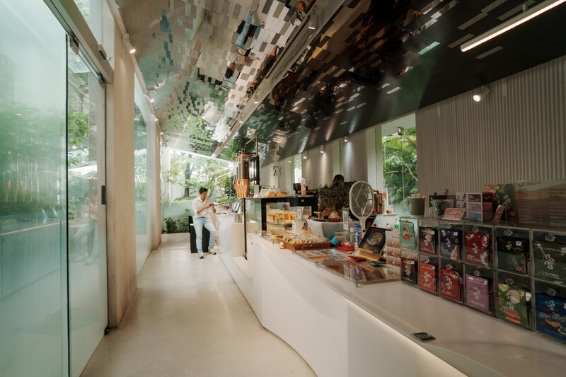 Modern gallery interior with long white counter display, industrial ceiling, and natural light from floor-to-ceiling windows.