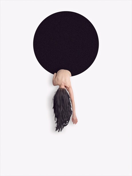 Woman with dark hair hanging upside down below a large black circle against white wall.