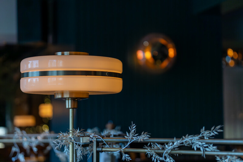 Mid-century modern pendant lamp with layered cream and chrome details, photographed against a dark interior backdrop.
