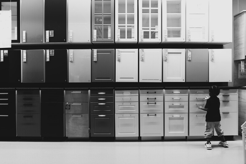 Person skateboarding in front of a wall displaying refrigerators in varying shades of black, white, and gray.