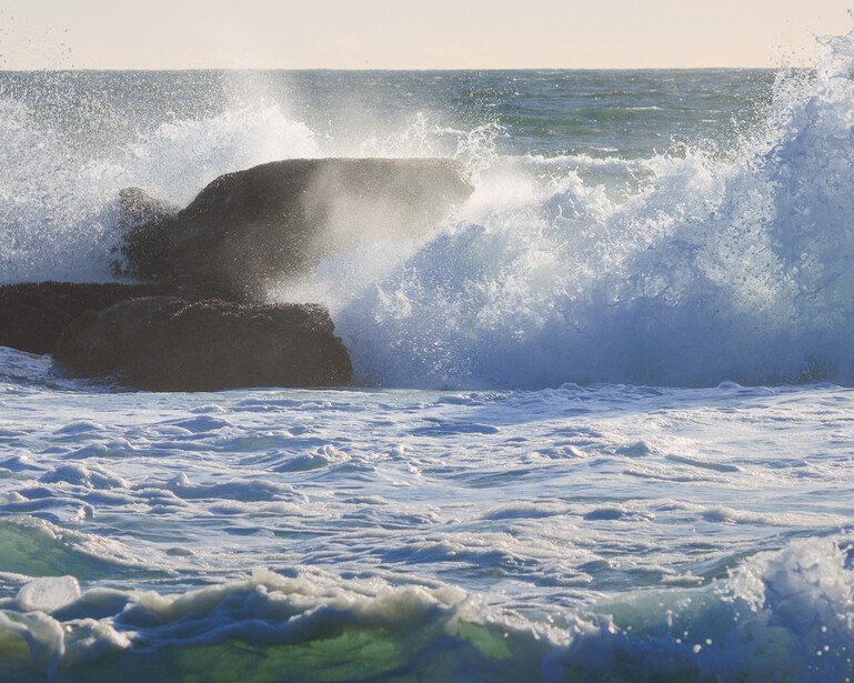Waves crashing over a rock on a the Pacific Coast beach