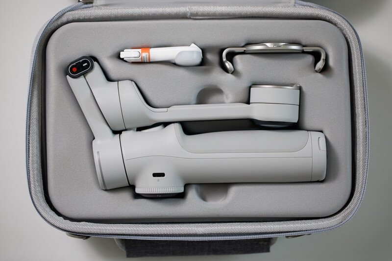 Overhead view of a gimbal stabilizer with accessories organized in a gray carrying case.