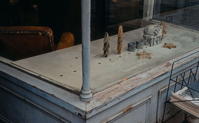 Weathered storefront counter with clothespins, wooden objects, and scattered items on concrete surface.