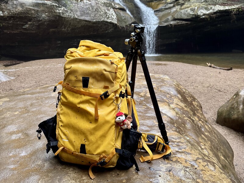 camera bag in the rain in front of waterfall
