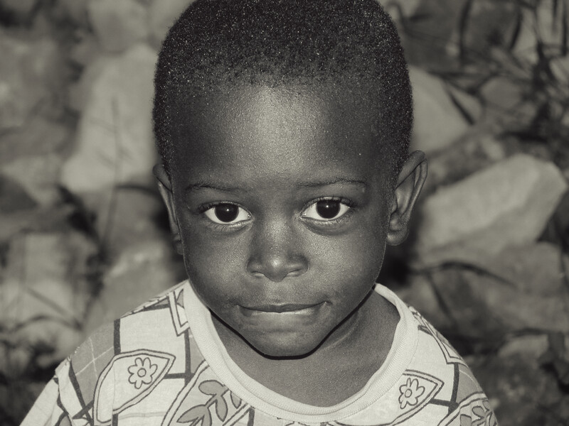 Young child with direct gaze looking at camera in black and white portrait.