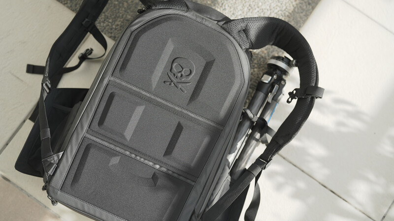 Gray camera backpack with organized compartments and shoulder straps, viewed from above on a light surface.