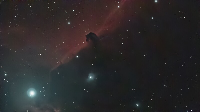 Dark nebula silhouetted against glowing red and teal emission nebulae with scattered stars.