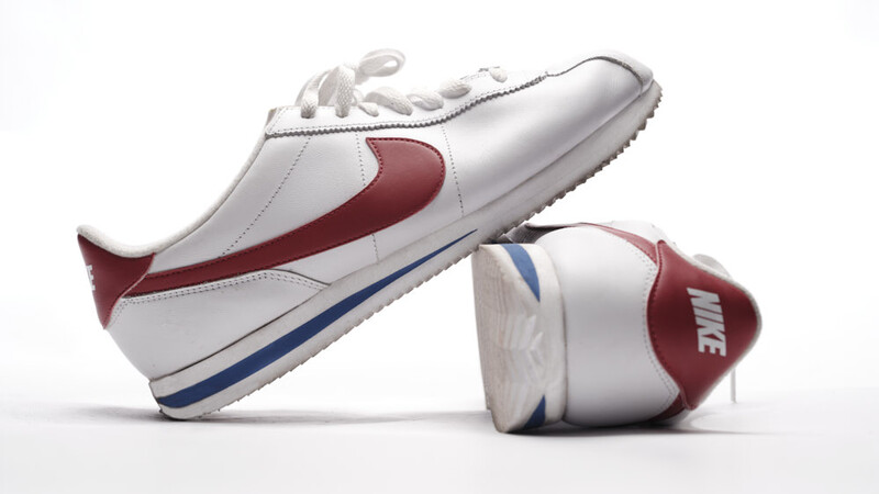 Two white sneakers with maroon and navy accents displayed against a white background.