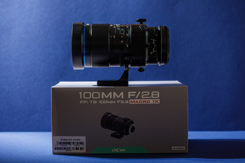 Laowa 100mm f/2.8 macro lens displayed on its retail box against a blue backdrop.