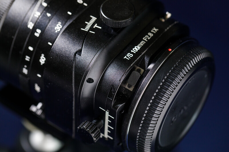Close-up of professional cinema lens with focus ring and depth-of-field markings on dark background.