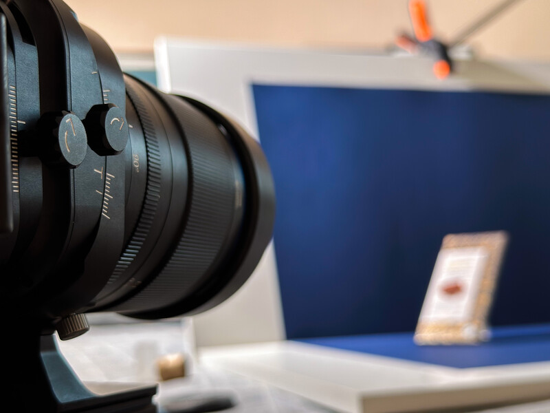 Wide-angle lens in sharp focus on a studio desk with blurred blue backdrop and mobile device behind.