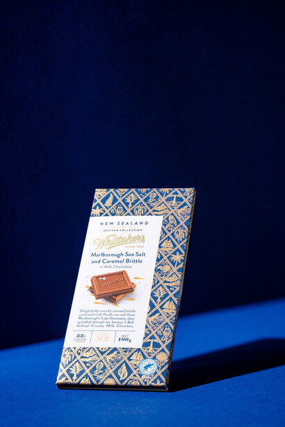 Product packaging with geometric pattern displayed at an angle on blue surface against dark background.