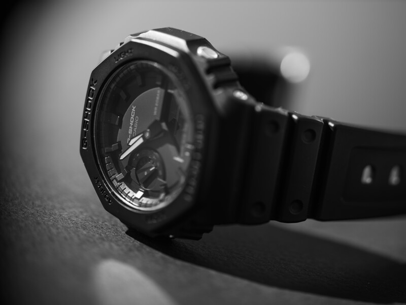 Digital sports watch with black rubber band displayed at an angle on a textured surface.