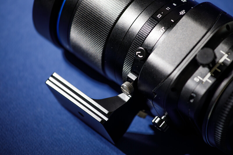 Telephoto lens with focus ring and depth-of-field scale markings on blue background.