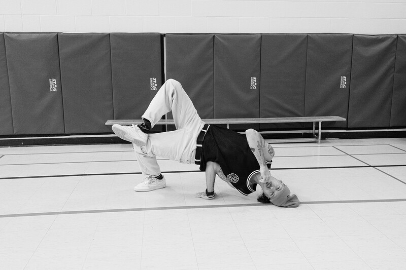 Two people practicing Brazilian Jiu-Jitsu grappling on an indoor mat with dark padding in background.