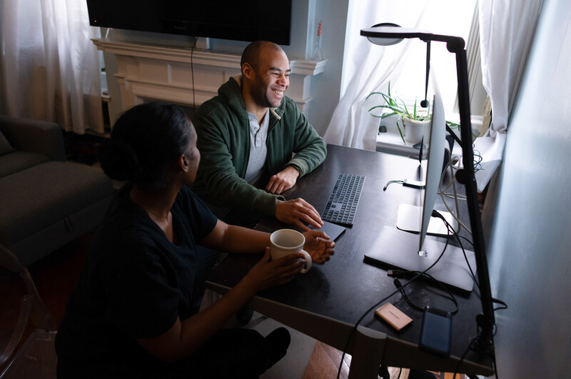 Man and woman in dark room looking at a computer screen.