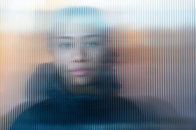 Abstract portrait with vertical line scan effect creating a distorted, pixelated appearance of a person's face.