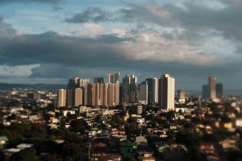 Urban skyline with high-rise buildings silhouetted against dramatic cloudy sky at dusk.