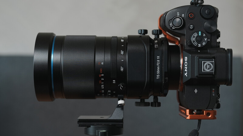Sony mirrorless camera with telephoto lens mounted on tripod head against neutral background.