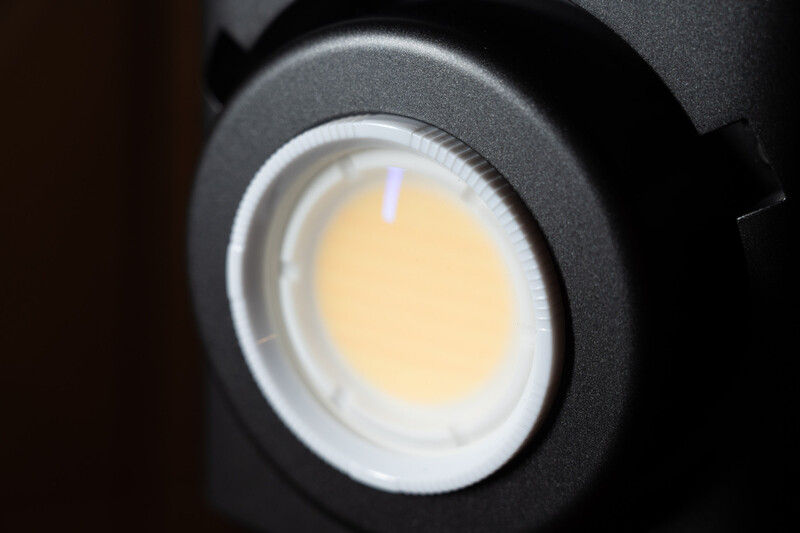 Close-up of a studio light fixture with warm-toned lamp head and dark housing.