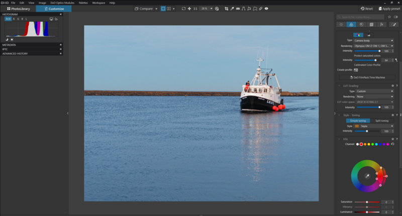 Red and black tugboat navigating calm blue water alongside a wooden pier structure.