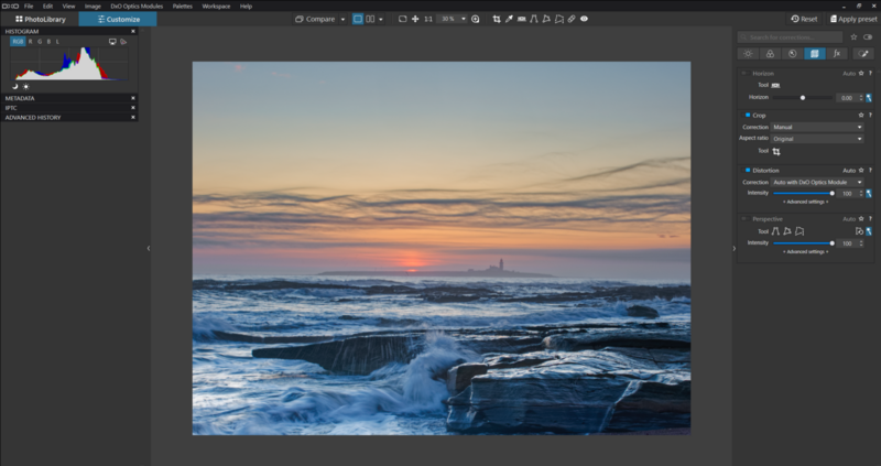 Seascape at sunset with waves crashing against rocky shore and warm orange sky.