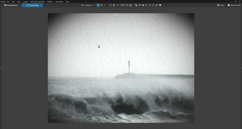 Stormy ocean waves crashing with a lighthouse visible through heavy mist in the distance.