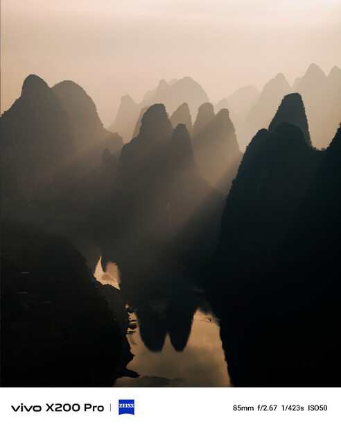 Dramatic silhouettes of jagged mountain peaks rising through thick morning mist with a misty river valley below.