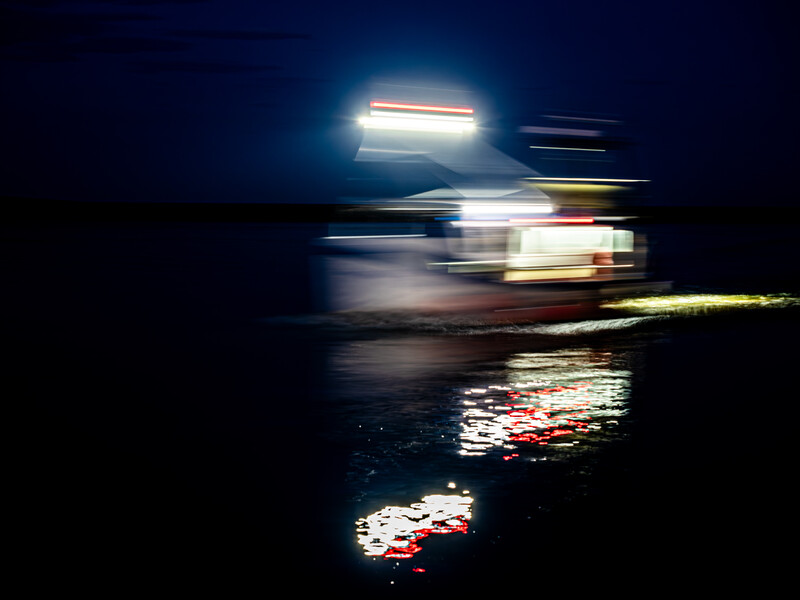 Night scene with motion-blurred vehicle headlights and taillights streaking across dark pavement.