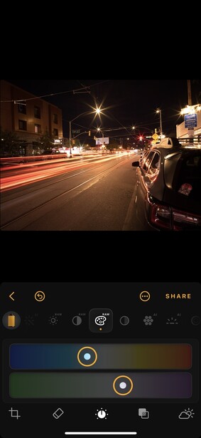 Screenshot of mobile photo editing interface showing night street scene with light trails.