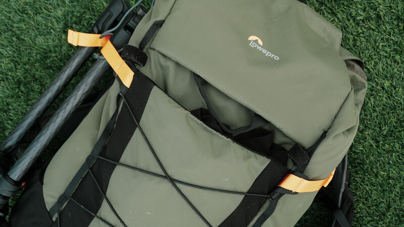 Lowepro camera backpack with yellow compression straps displayed on green artificial turf.
