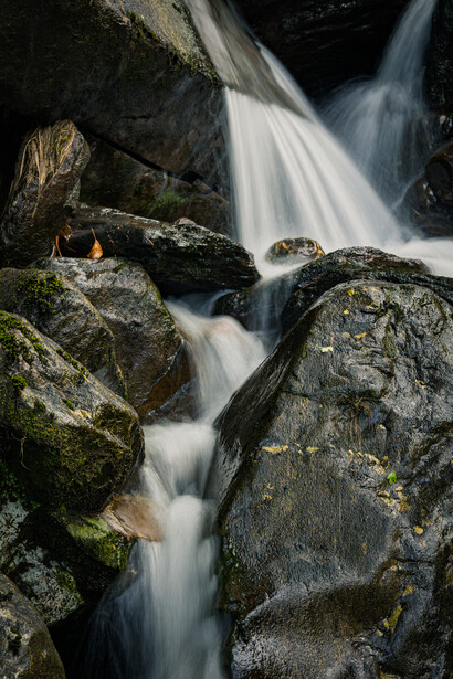 Smooth waterfall cascading over moss-covered rocks in a forest stream.