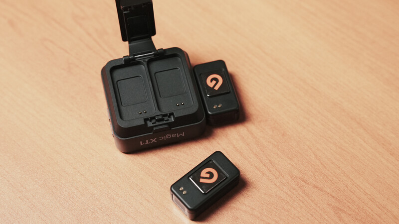 Luxsiren dual-battery charger with two battery slots and remote control on wooden surface.