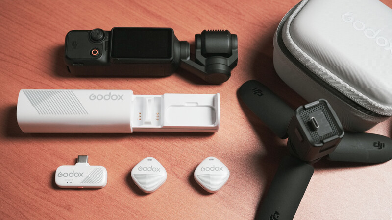 Godox wireless microphone system components arranged on coral background.