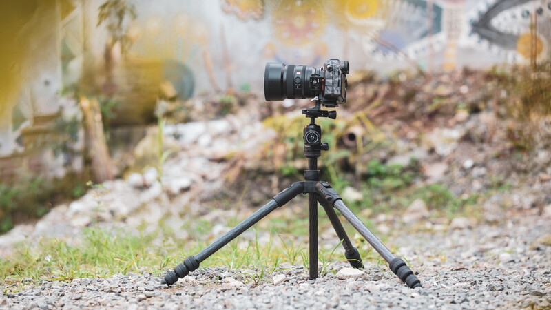 DSLR camera mounted on a compact tripod positioned on gravel outdoors.