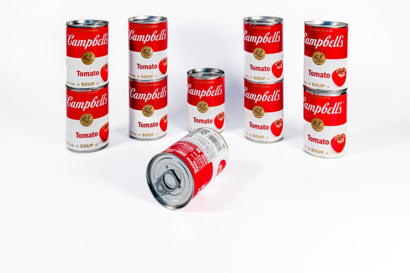 Campbell's tomato soup cans arranged in a circle with one can lying on its side in the center.
