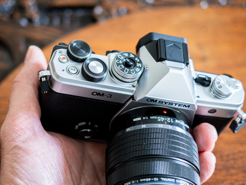 Two vintage rangefinder cameras held in hands, showing chrome top plates and mechanical controls.