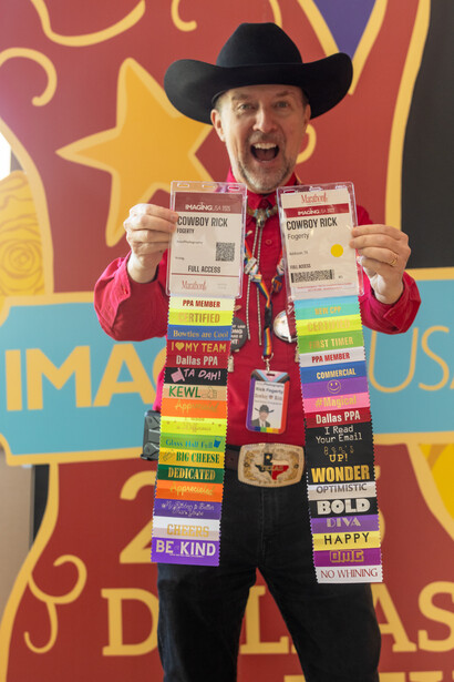Man in cowboy hat and red jacket displaying stacked cereal boxes against colorful backdrop.