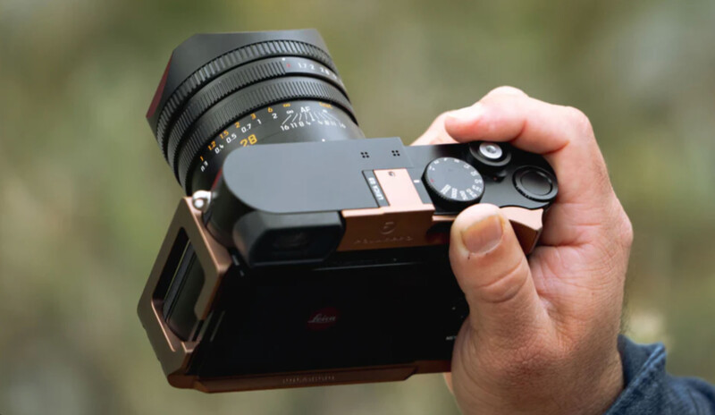 Photographer's hand holding a rangefinder camera with a manual focus lens mounted on top.