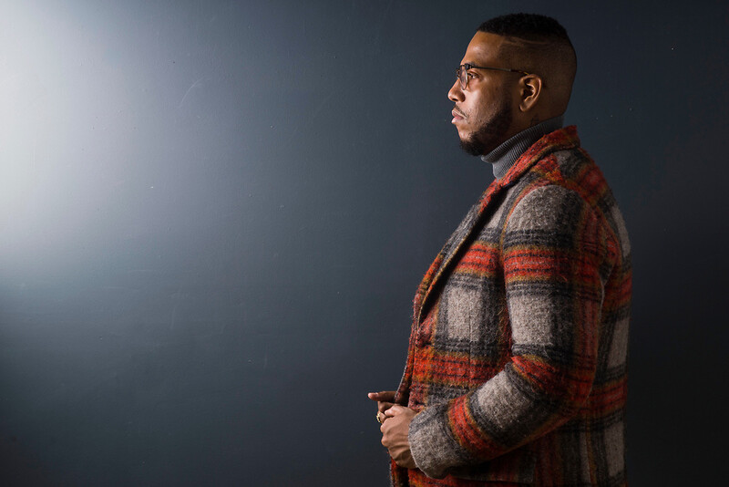 Man in plaid shirt against neutral background, photographed in profile with studio lighting.