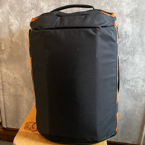 Black cylindrical camera bag with orange accent straps and carrying handle.