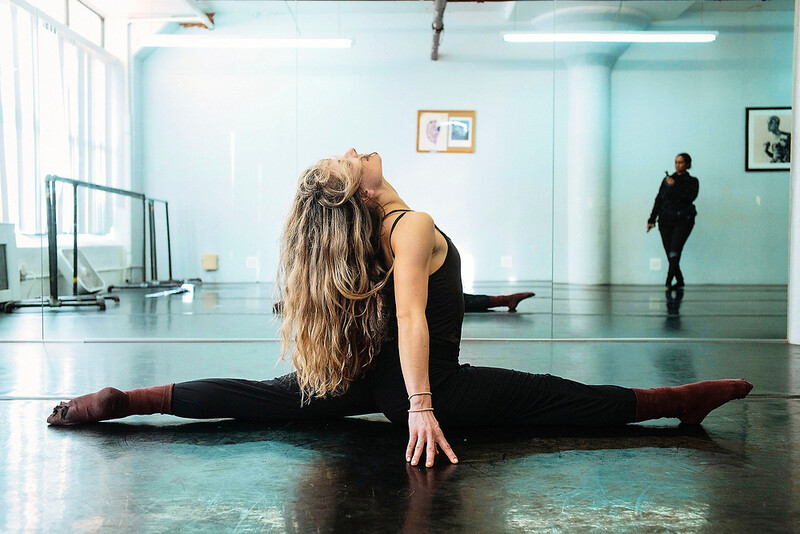 Dancer in deep forward fold performing full splits on a studio floor.